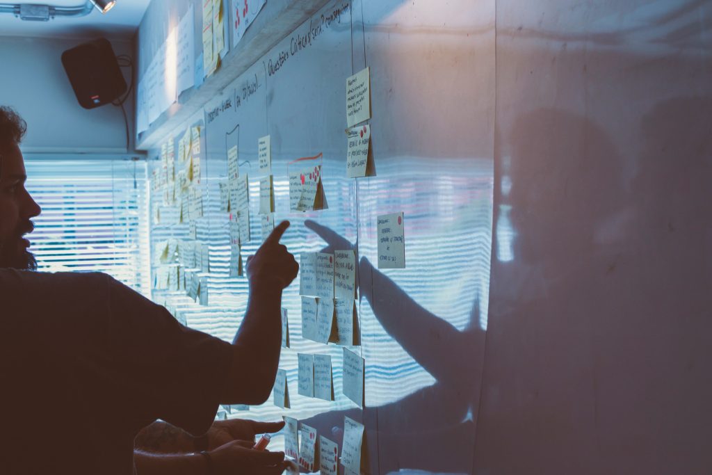 Man pointing at a whiteboard covered in sticky notes.