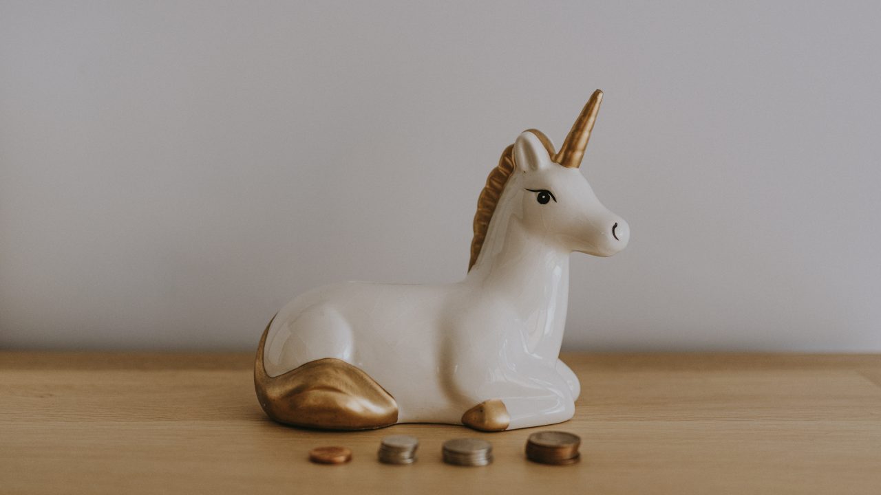 unicorn money box on a desk with coins